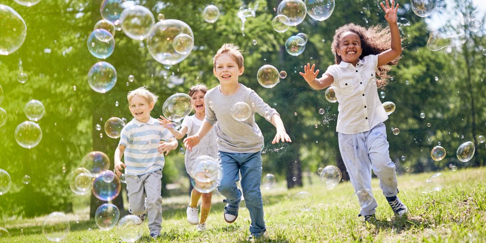 Enfants courant après des bulles de savon dans un parc 