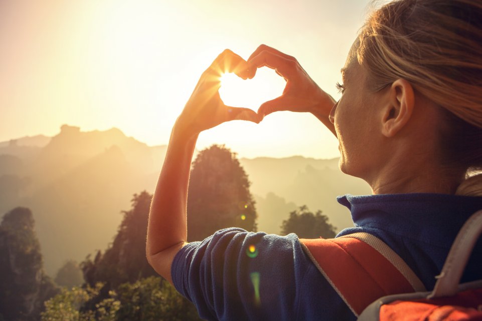 Femme faisant un coeur face au soleil