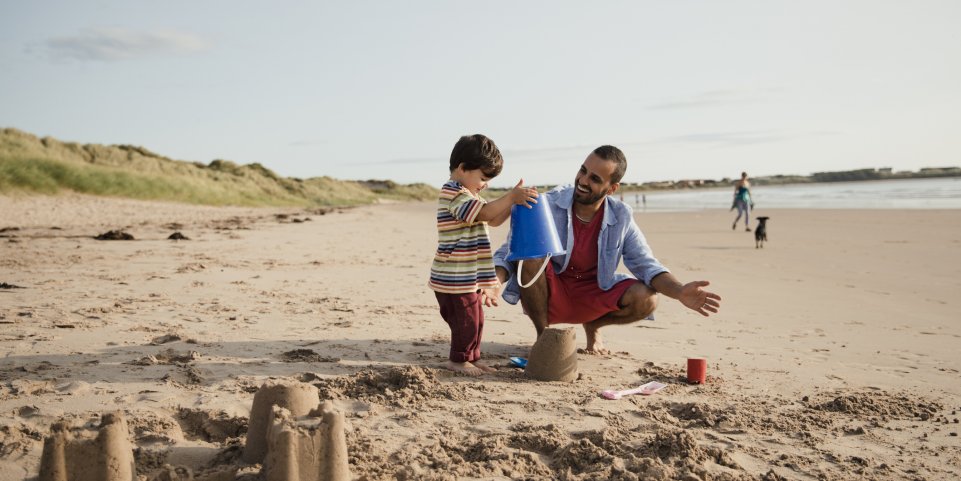 père et fils à la plage et château de sable 