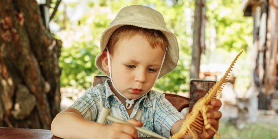 Enfant avec un faux squelette de dinosaure