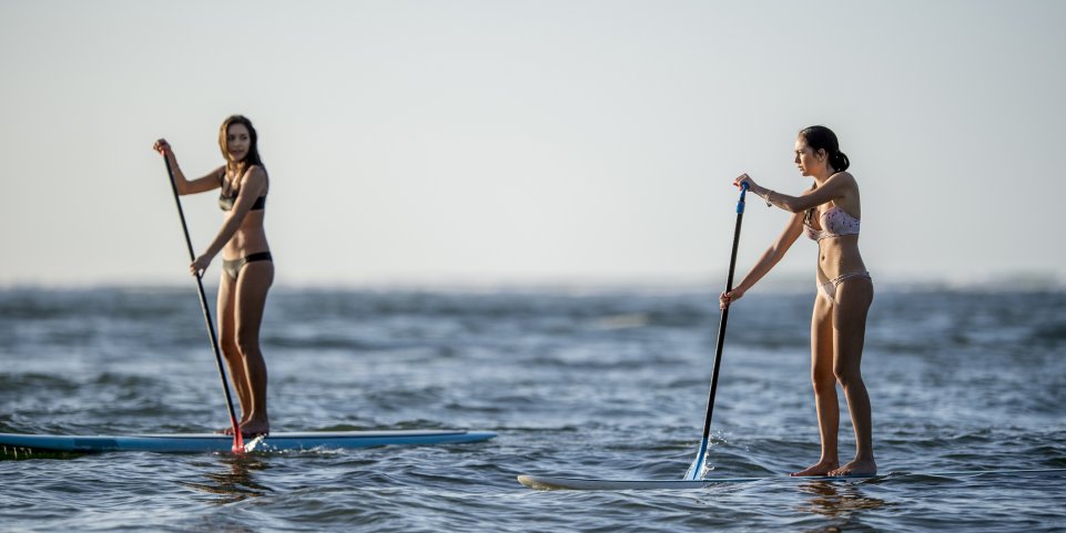 femmes qui font du paddle en mer