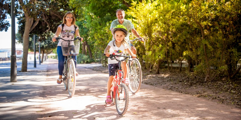 Un père et ses filles à vélo en bordure de forêt