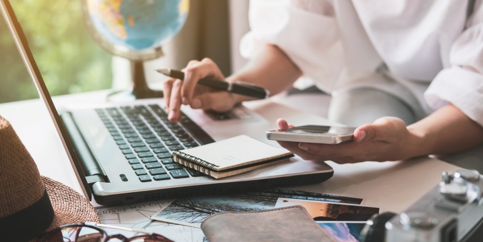 femme qui organise son voyage sur téléphone et ordinateur