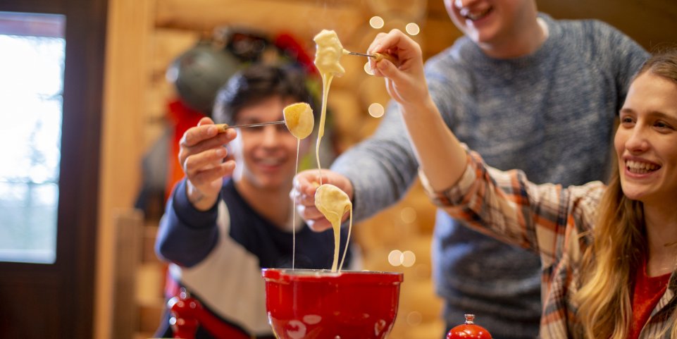Des amis dégustent une fondue savoyarde pendant des vacances au ski.