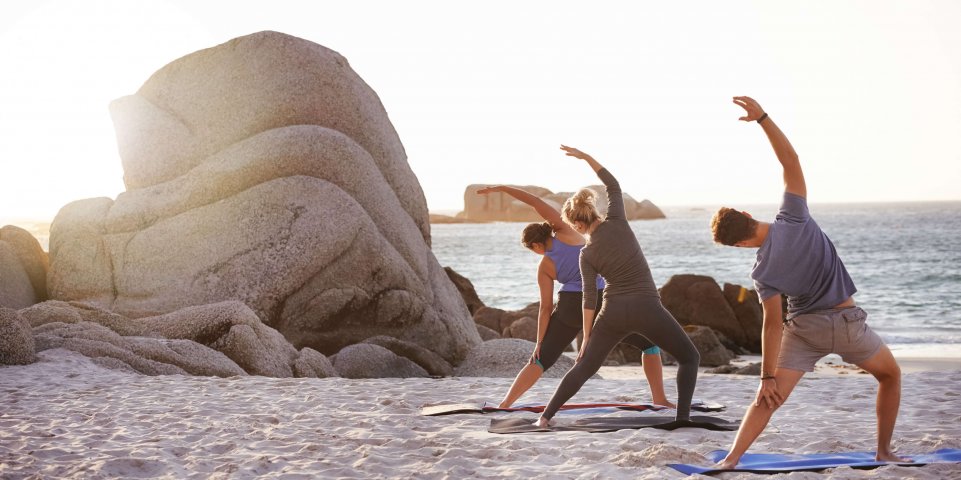 Un groupe fait du yoga à la plage