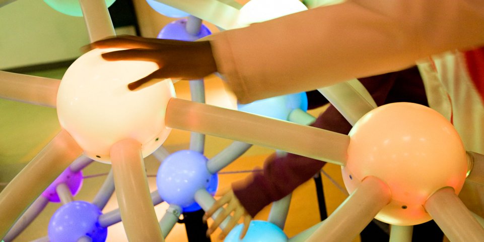 Sciences au musée : mains d'enfants sur une structure de boule reliée de tubes
