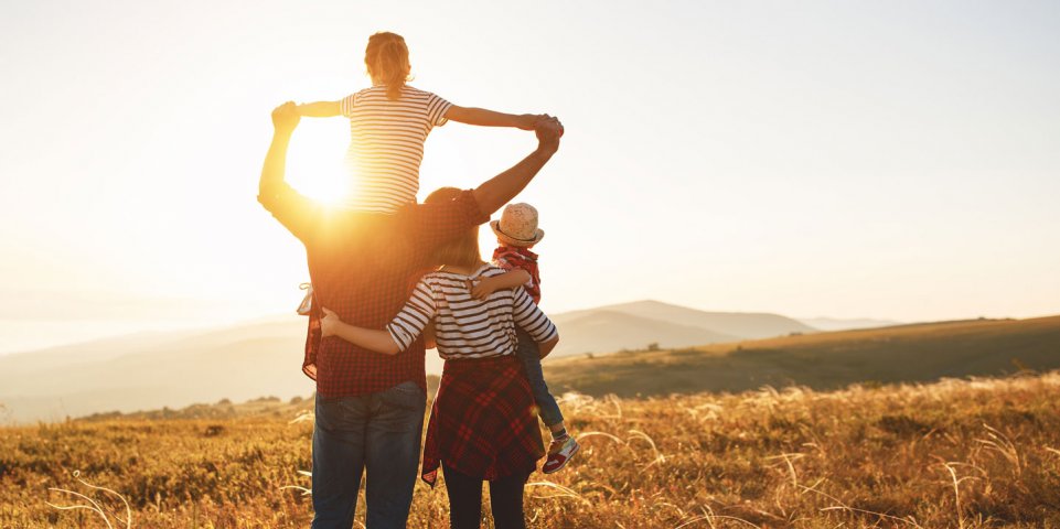 Famille dans un champs devant un coucher de soleil