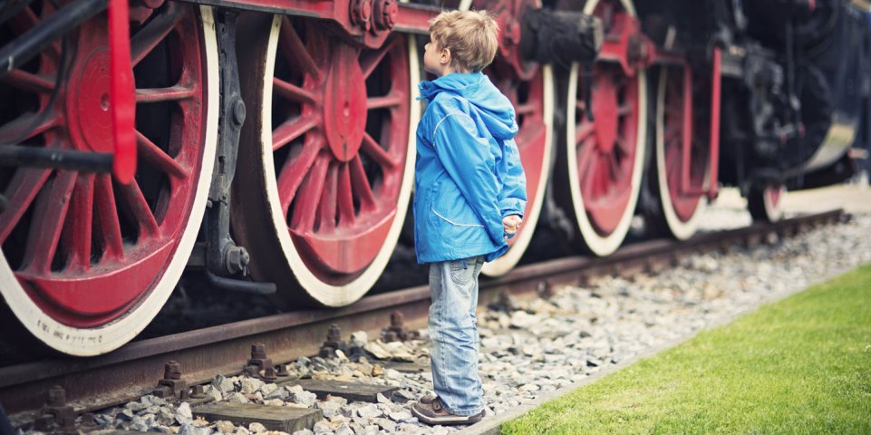 enfant devant les roues d'un train à vapeur