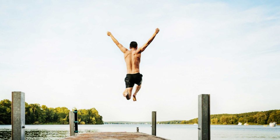 homme saut sur ponton lac