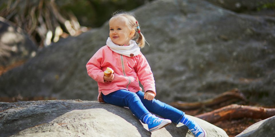 Petite fille sur un rocher en forêt