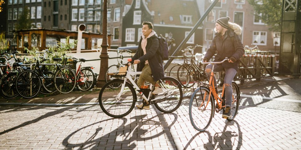 Deux hommes se promènent à vélo près des canaux d'Amsterdam, aux Pays-Bas