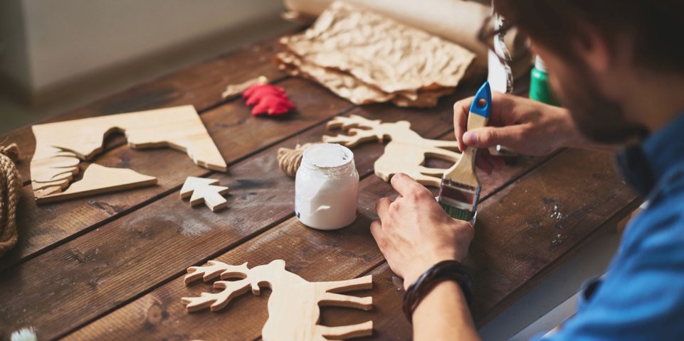 artisan qui fabrique un objet en bois en forme de renne