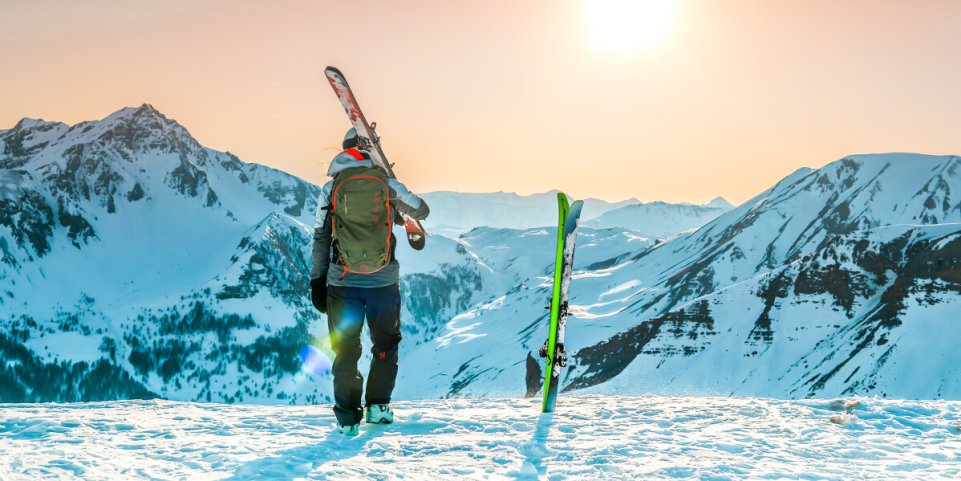 skieur sur la montagne enneigée marche vers le soleil, ski à l'épaule