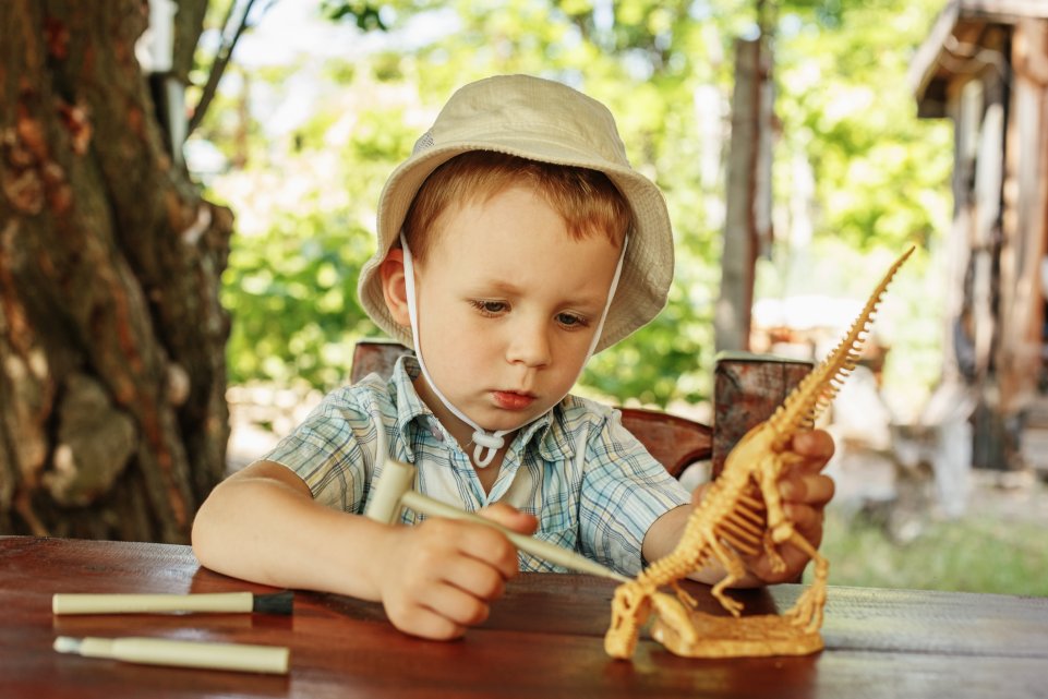 Enfant avec un faux squelette de dinosaure